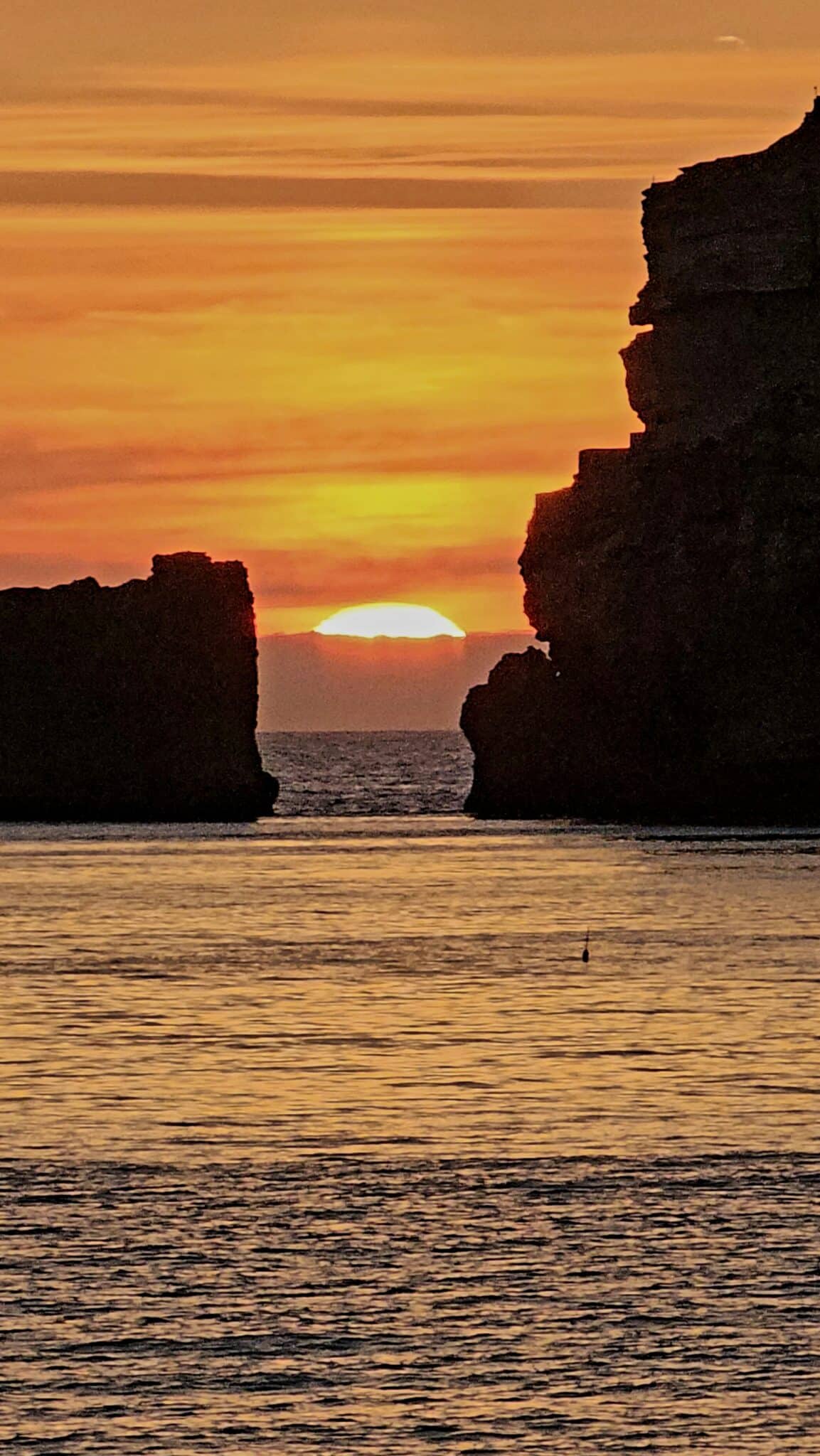 Sun goes down between the cliffs in Nazare by Paulo Figueira